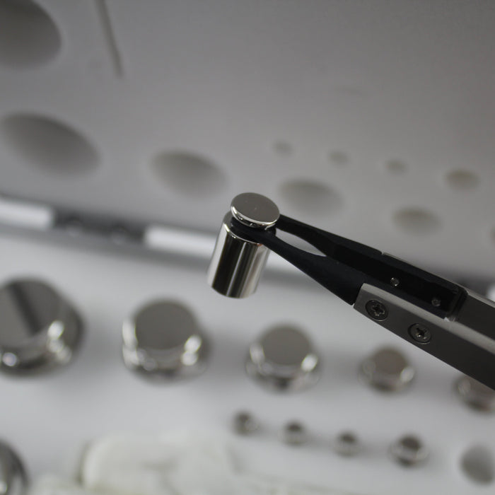 weighing scale calibration weight held by tweezers